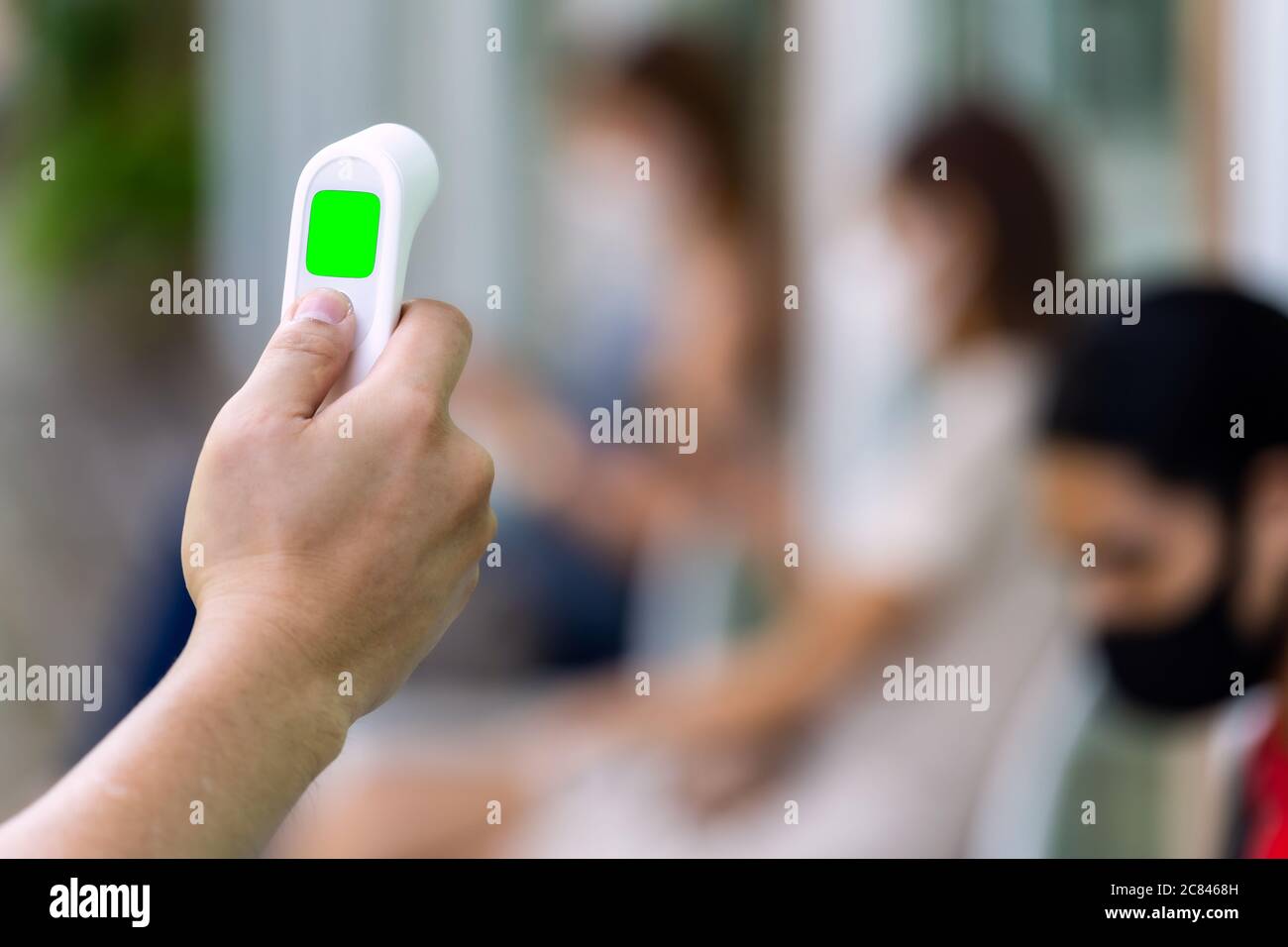 Gros plan sur le thermomètre à main avec l'arrière-plan du client, asseyez-vous sur la chaise de social et attendez son appel. Nouveau concept de restaurant normal. Banque D'Images