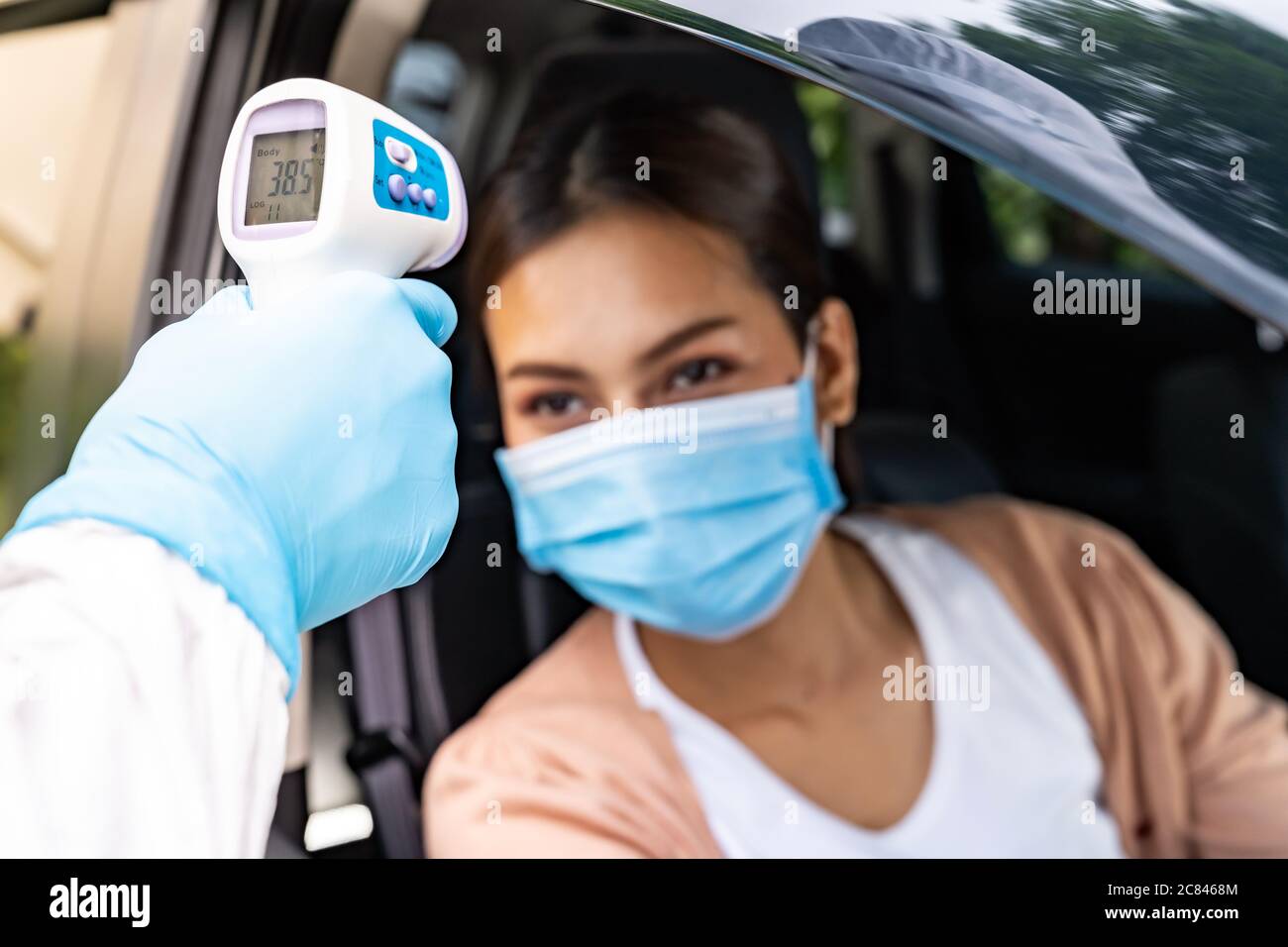 Le personnel médical ayant un EPI prend la température pour la fièvre chez une femme asiatique avant le test du coronavirus Covid-19 au poste de passage au volant de l'hôpital. Nouvelle santé normale Banque D'Images