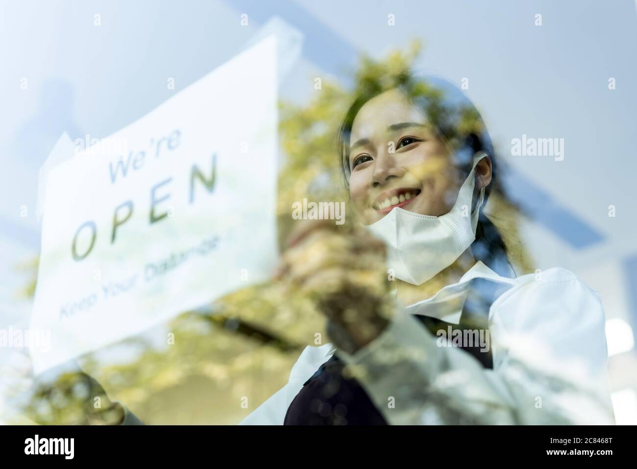 Serveuse asiatique mettant sur une signalisation ouverte avec distance sociale pour un nouveau restaurant normal. Nouveau concept de style de vie normal du restaurant. Banque D'Images