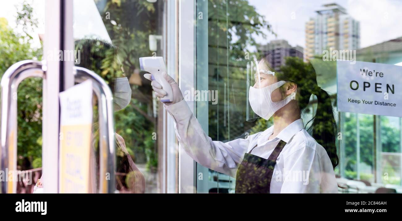 Serveuse asiatique avec masque facial Prenez la température au client avant d'entrer au restaurant. Restaurant Nouveau concept de style de vie normal de restaurant après coro Banque D'Images