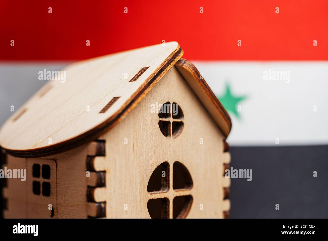 Petite maison en bois, drapeau syrien sur fond. Concept immobilier, attention douce Banque D'Images