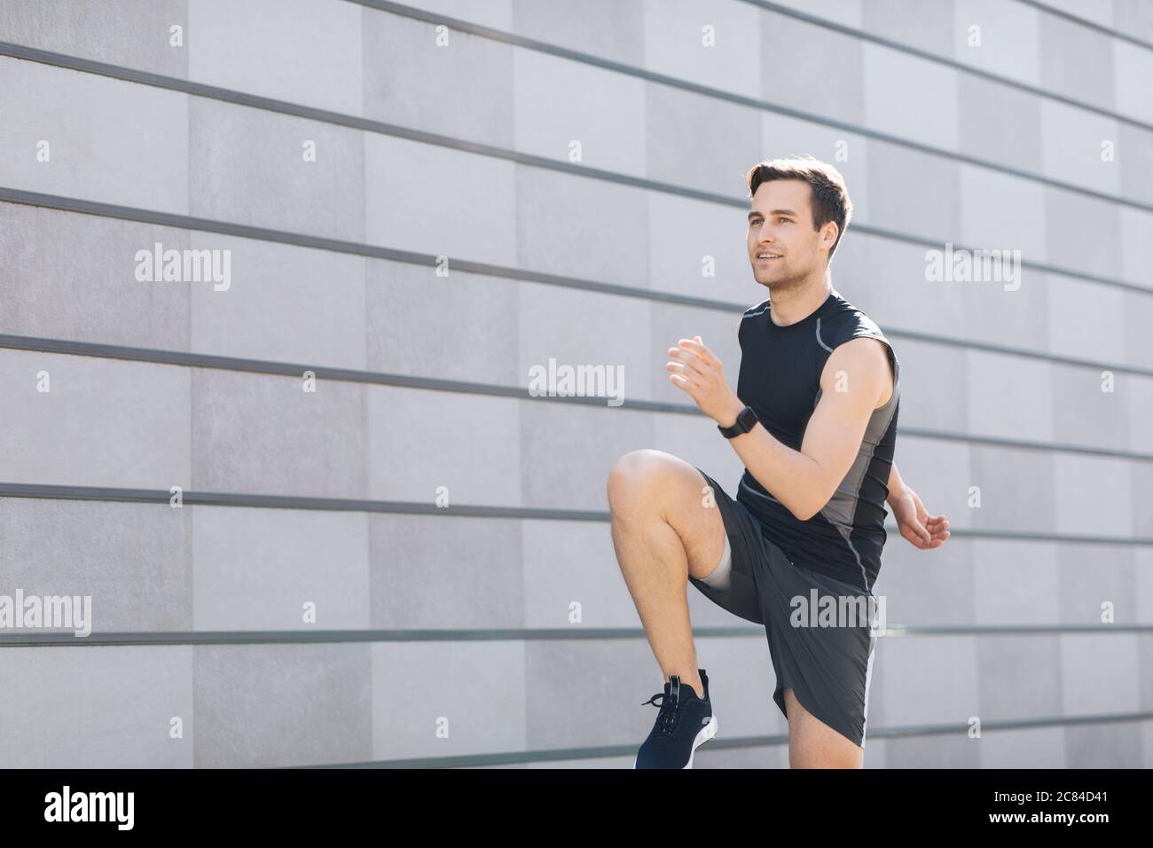 Style urbain. Homme avec tracker d'activité va pour le sport sur fond gris mur Banque D'Images