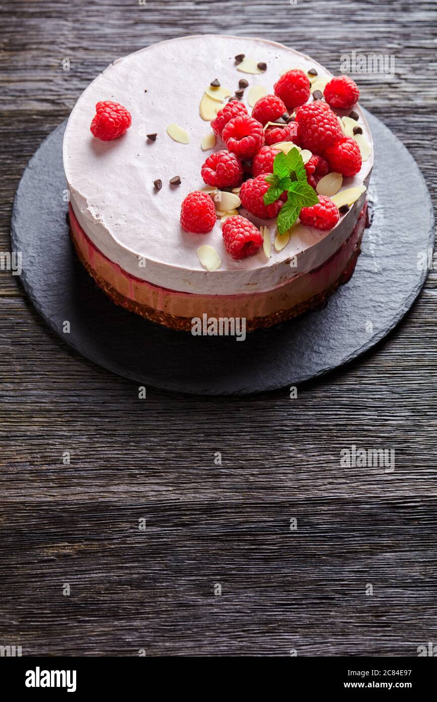 gâteau à la crème glacée à la framboise sur une assiette noire en ardoise sur une table en bois sombre, vue verticale depuis le dessus Banque D'Images