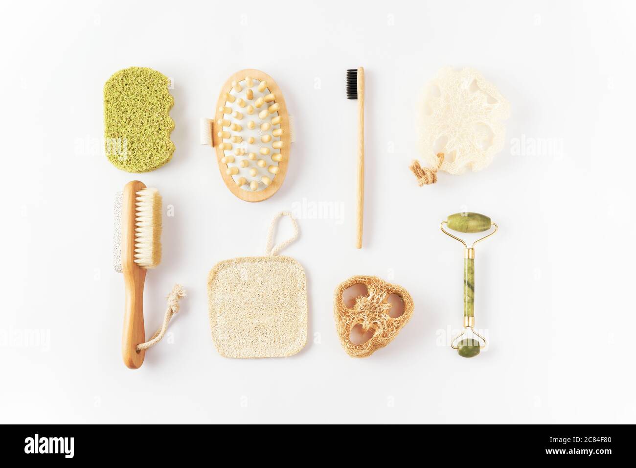 Articles écologiques sur surface blanche. Brosse à dents en bambou, brosse à cheveux démêlante, éponge exfoliante, brosse massante, rouleau de visage en quartz. Banque D'Images