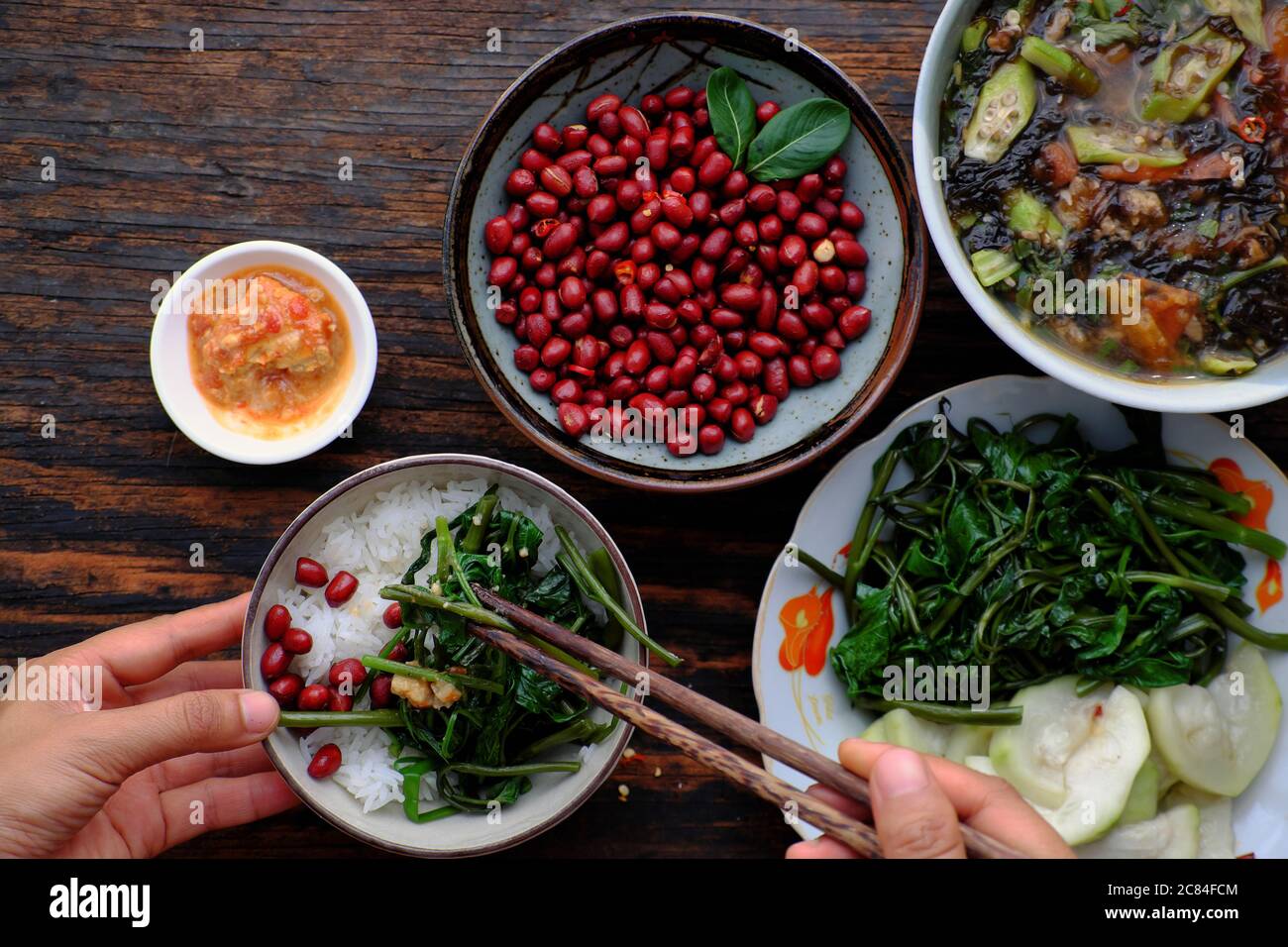 Vue de dessus les gens ont déjeuner, main tenir bol de riz avec fond végétarien vietnamien, arachides frites, soupe d'algues, plat bon pour la santé Banque D'Images
