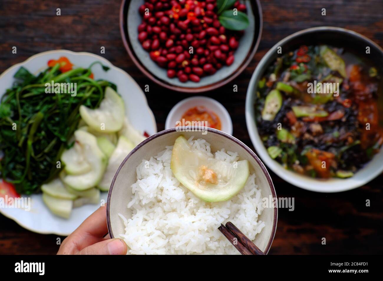 Vue de dessus les gens ont déjeuner, main tenir bol de riz avec fond végétarien vietnamien, arachides frites, soupe d'algues, plat bon pour la santé Banque D'Images