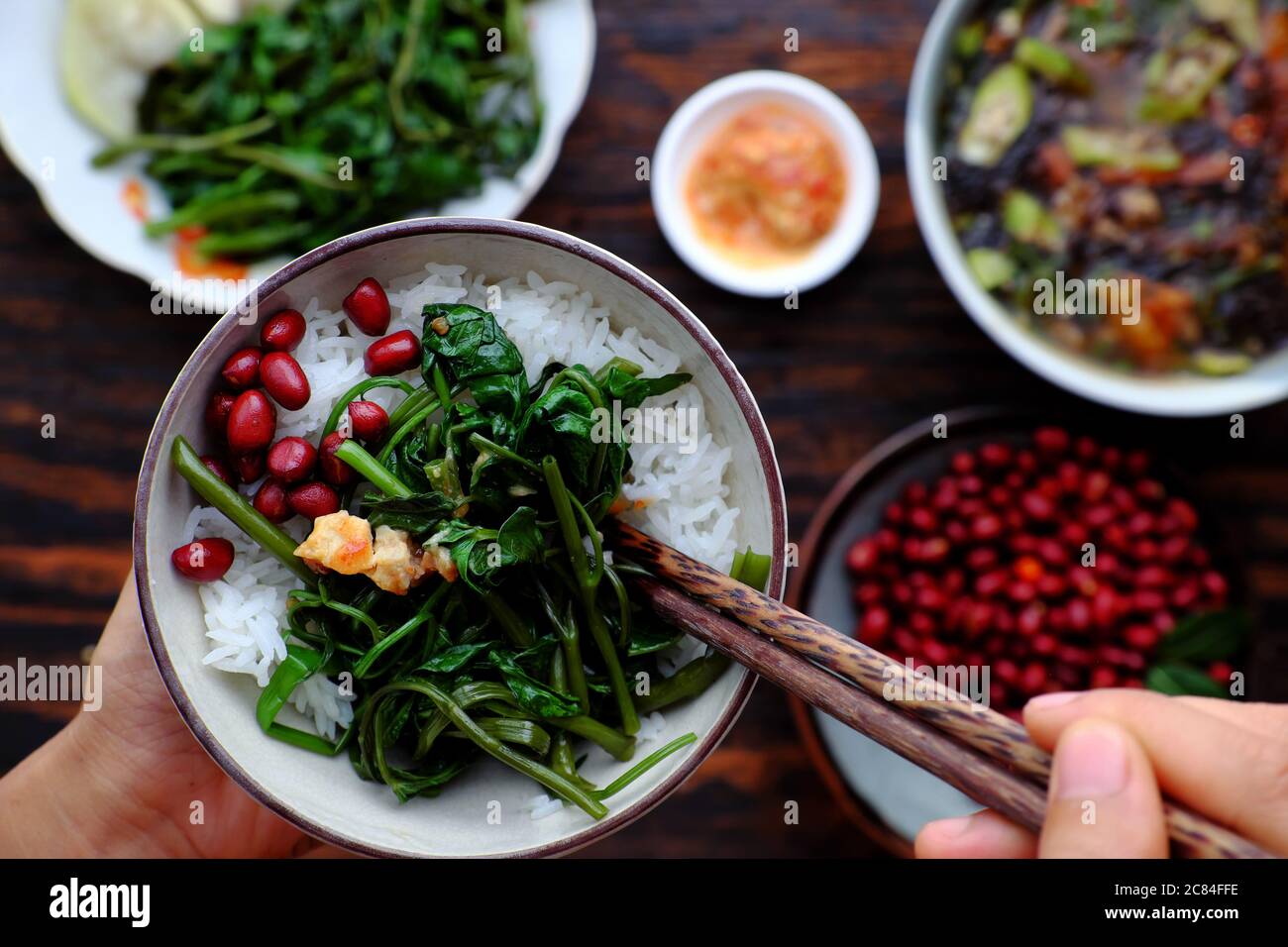 Vue de dessus les gens ont déjeuner, main tenir bol de riz avec fond végétarien vietnamien, arachides frites, soupe d'algues, plat bon pour la santé Banque D'Images