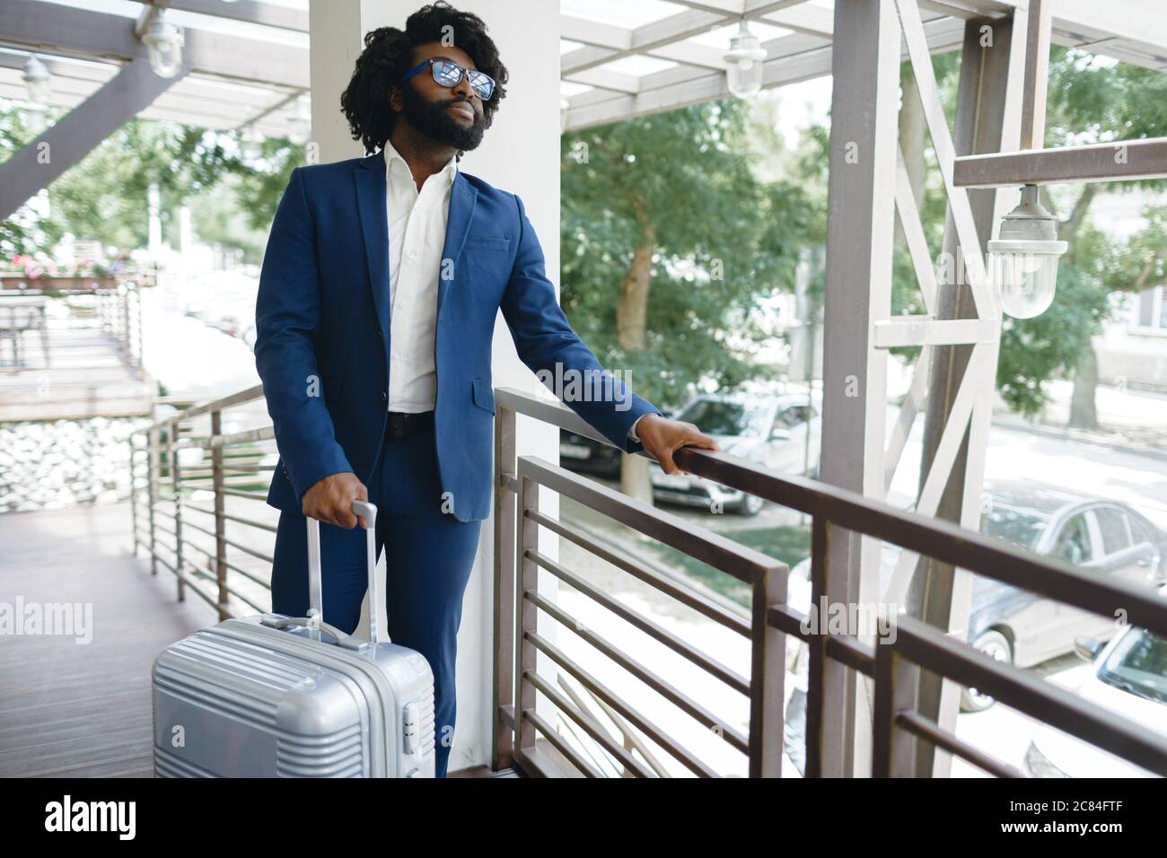 Homme noir en costume habillé avec une valise emballée entrant dans la ...