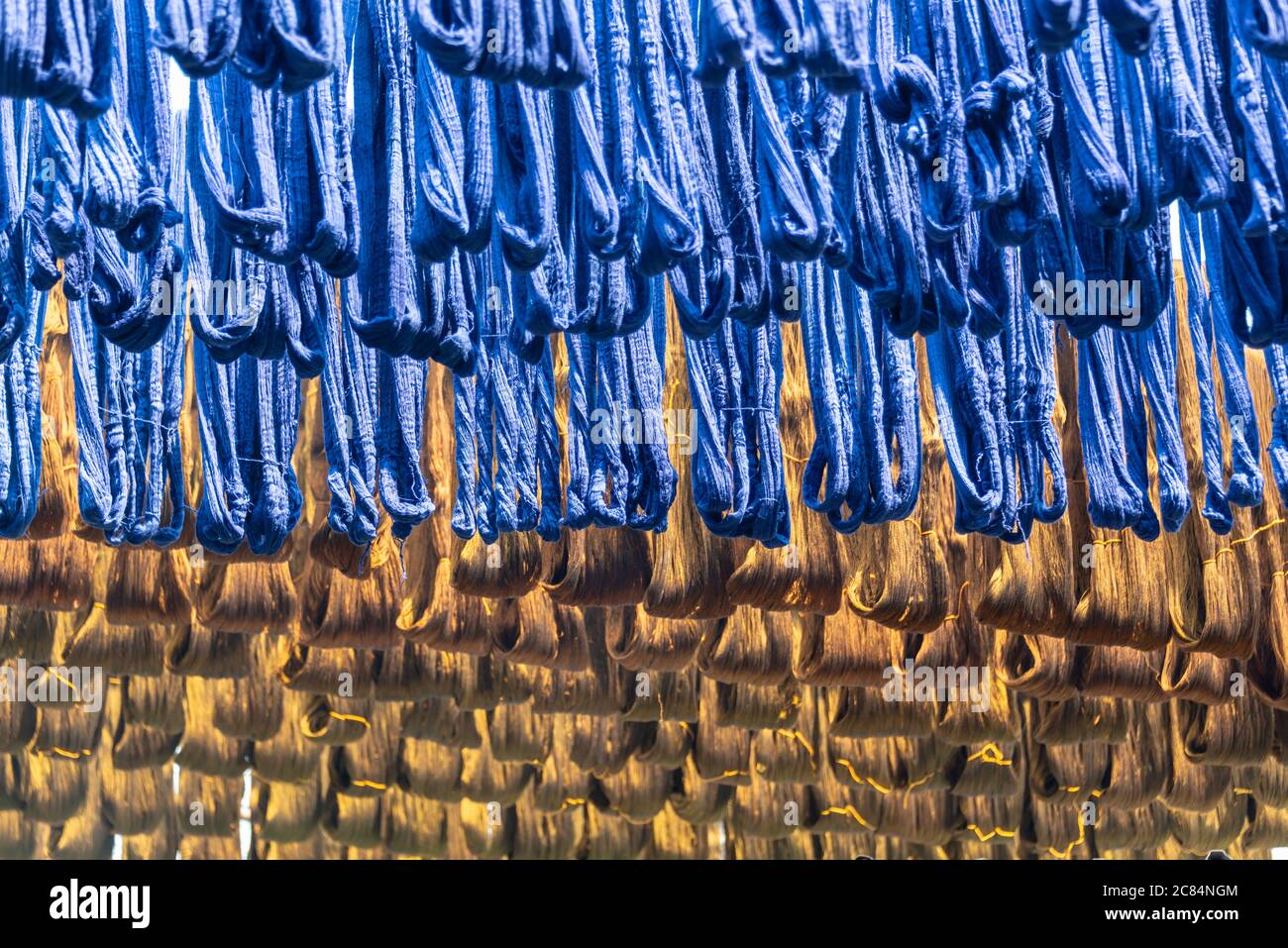 Soie teint bleu suspendue dans une usine de tissage de tissus à Amarapura, Myanmar Banque D'Images