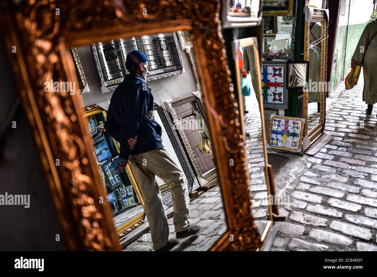 Maroc, Tétouan : scène de la vie quotidienne avec des habitants de la médina inscrite au patrimoine mondial de l'UNESCO. Boutique de miroirs. Réflexion d'un homme Banque D'Images