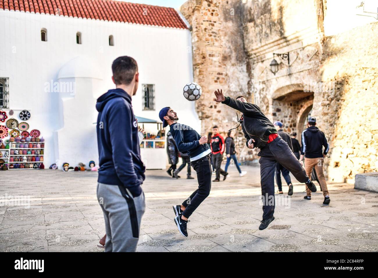 Maroc, Asilah: Station balnéaire à la pointe nord-ouest de la côte atlantique, au sud de Tanger. Groupe de jeunes jouant au football sur une place de la ville Banque D'Images