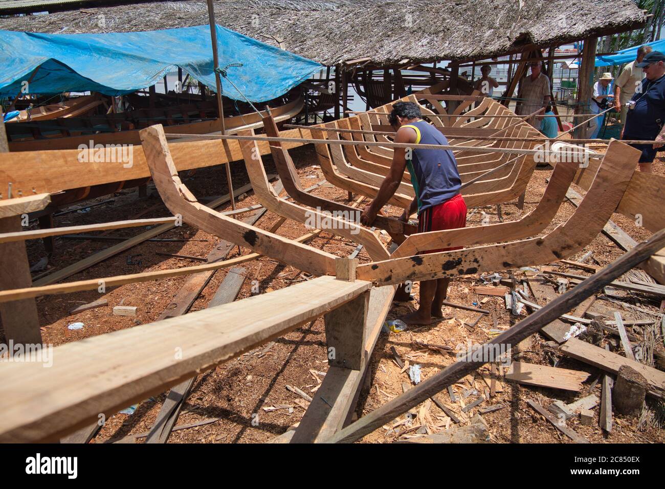 Le squelette d'un long canoë en bois construit sur une cour de bateau avec un homme qui travaille dessus, à Macapa, État d'Amapa, Brésil Banque D'Images