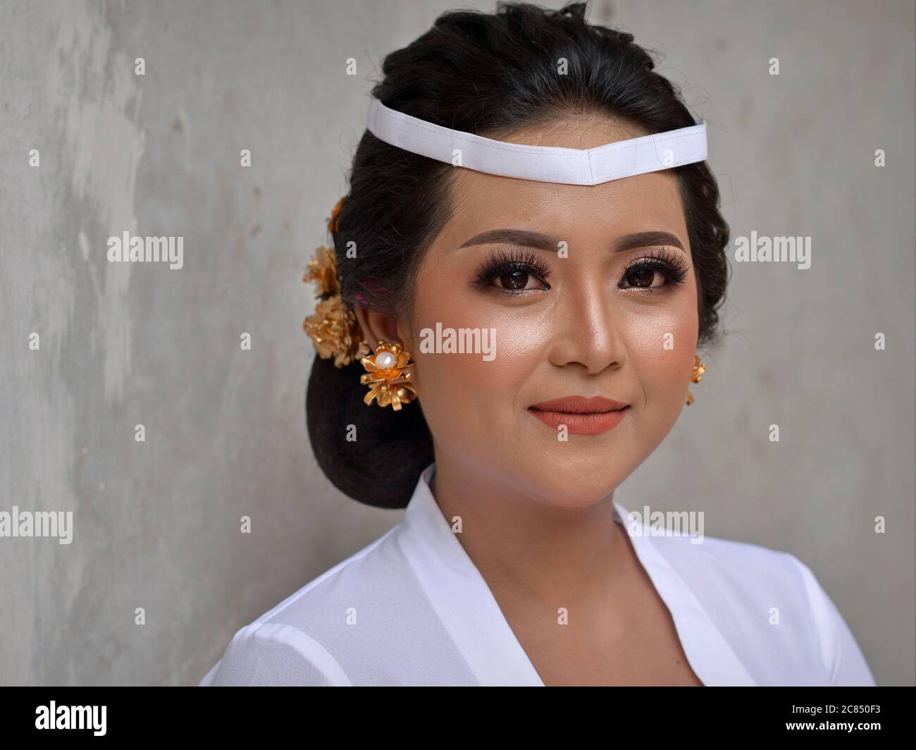 Belle femme indonésienne balinaise porte une tenue blanche et pose pour la caméra lors d'une cérémonie religieuse de temple hindou (festival Odalan). Banque D'Images