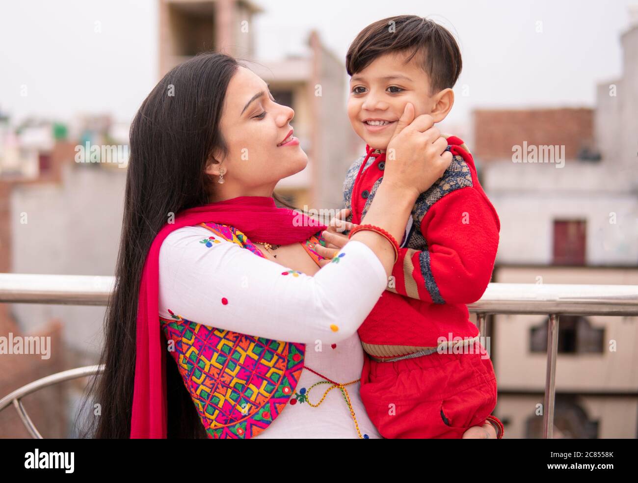 Belle, heureuse indienne jeune mère tirant les joues son petit fils coupé. Elle est debout près de la rampe et passe du temps libre avec son fils. Banque D'Images