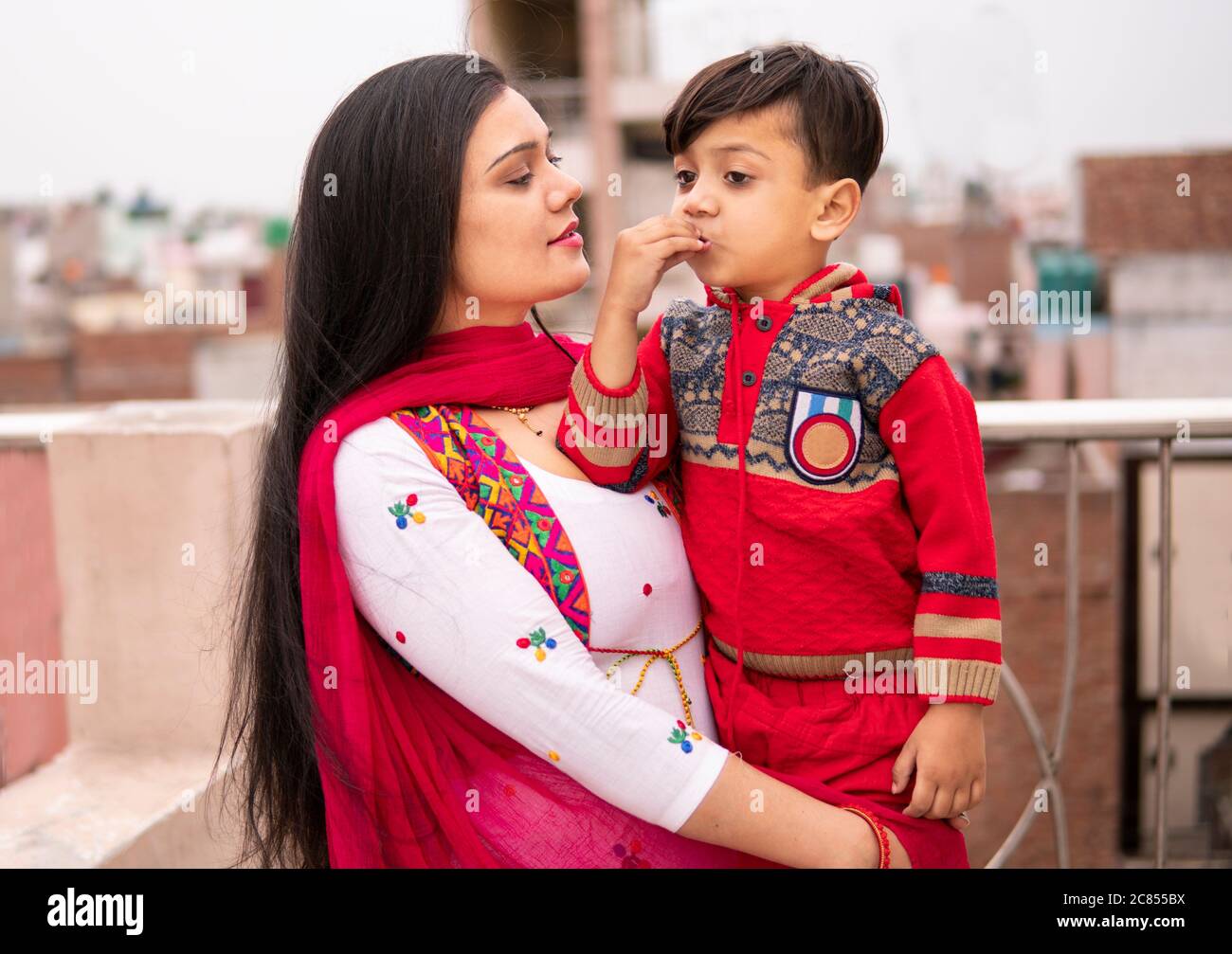 Belle et heureuse jeune mère indienne avec son petit fils coupé. Elle est sur le toit et passe du temps libre avec son fils. Elle porte une robe traditionnelle. Banque D'Images