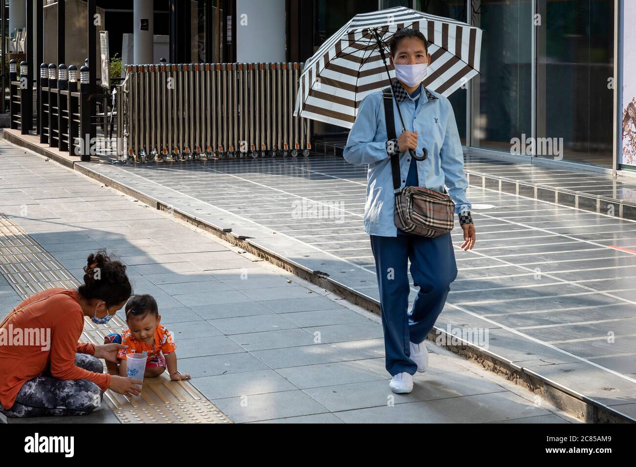 Femme portant un masque facial avec bébé mendiant dans la rue pendant la pandémie Covid 19, Bangkok, Thaïlande Banque D'Images