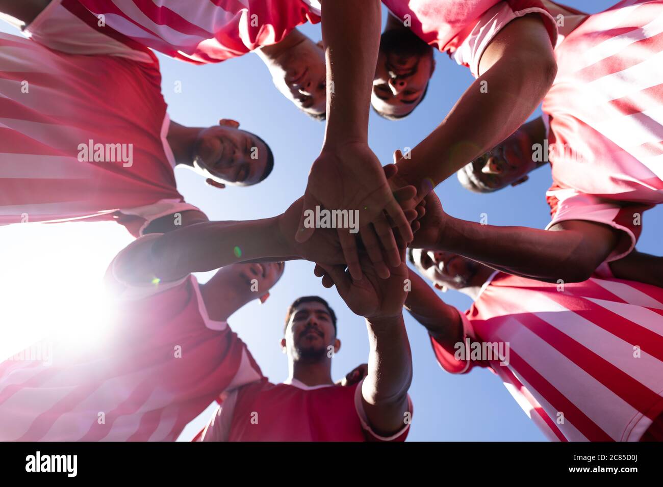 Vue à angle bas de l'équipe multi-ethnique de cinq joueurs de football de côté portant un entraînement de bande d'équipe sur un terrain de sport au soleil, debout à circl Banque D'Images