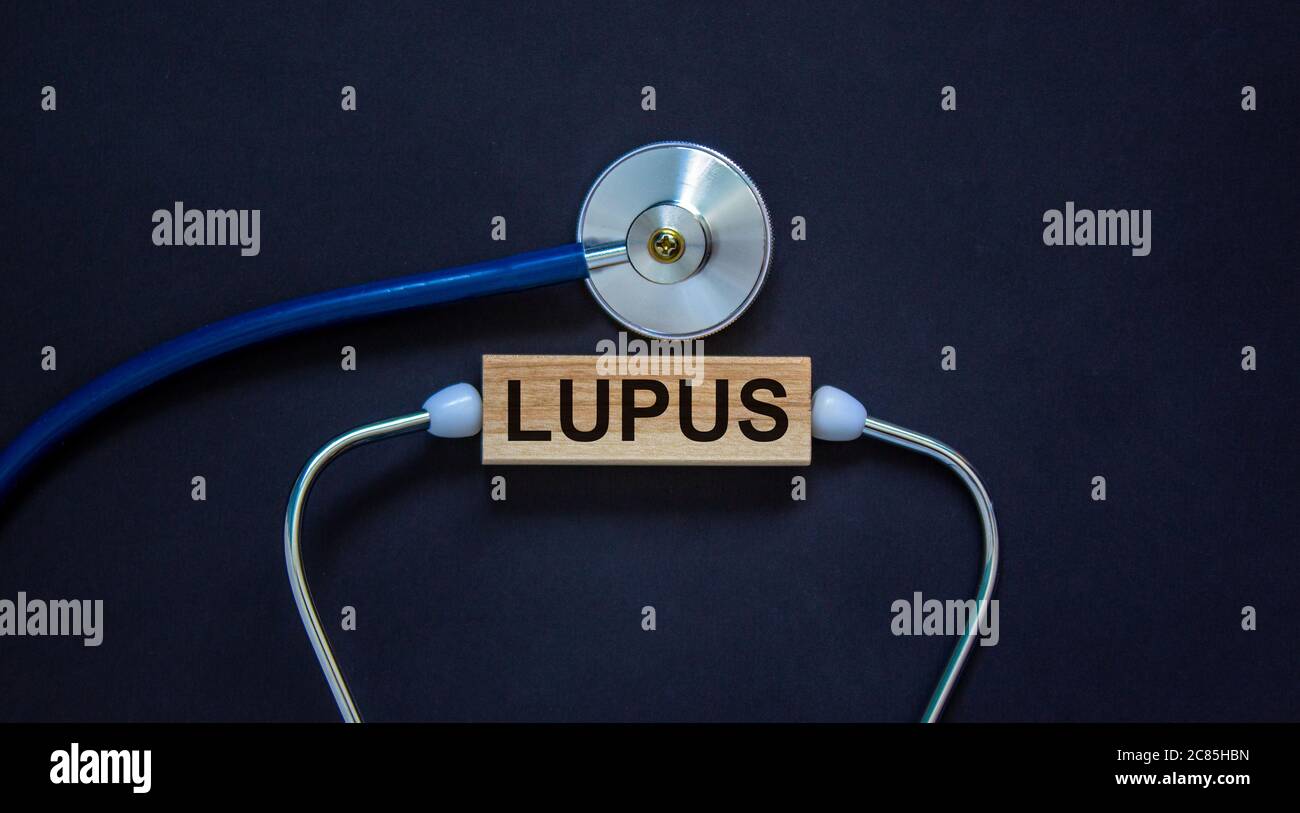 Bloc en bois avec le mot « lupus » et le stéthoscope sur fond noir. Concept médical. Banque D'Images
