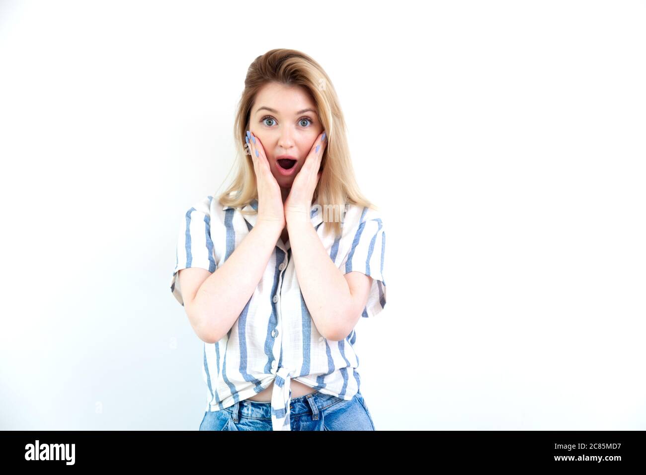 Surprisée jeune belle femme en vêtements décontractés sur fond blanc Banque D'Images