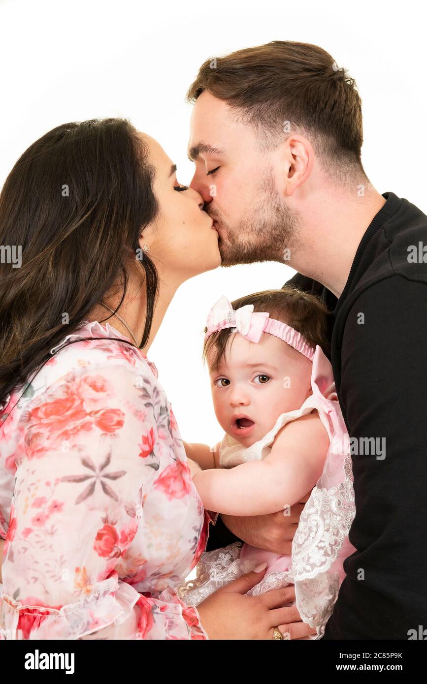 Portrait vertical de style de vie d'un jeune couple embrassant avec l'expression stupéfaite de leur fille sur son visage. Banque D'Images