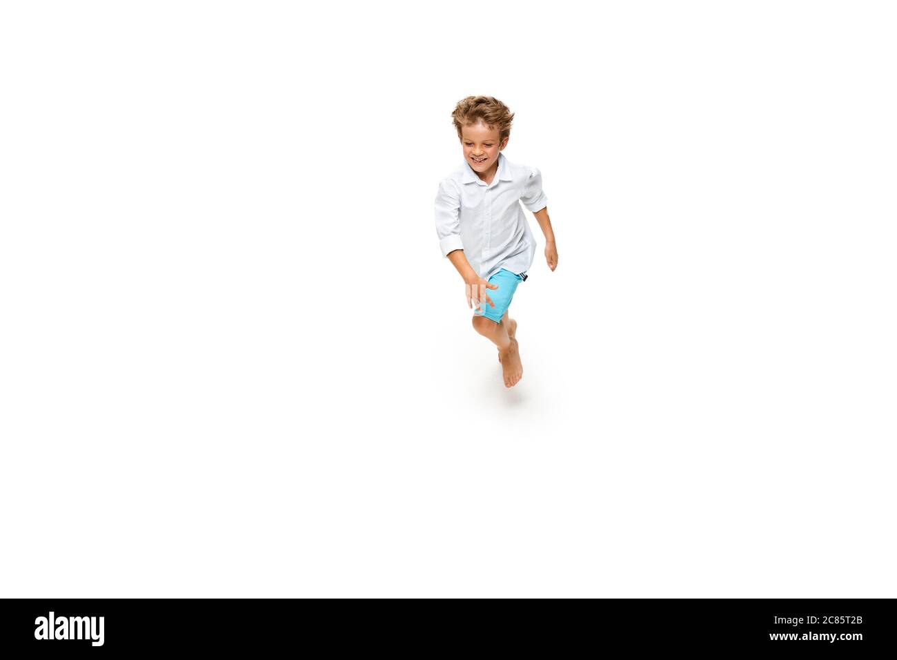 Enfant heureux, petit garçon caucasien émotif sautant et courant isolé sur fond blanc. Il a l'air heureux, gai, sincère. CopySpace pour publicité. Enfance, éducation, concept de bonheur. Banque D'Images