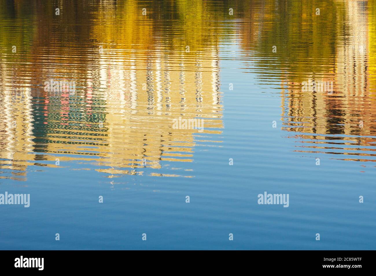 Réflexion de bâtiments et d'arbres dans l'eau, rivière, étang, lac en automne, ciel bleu, jour ensoleillé Banque D'Images