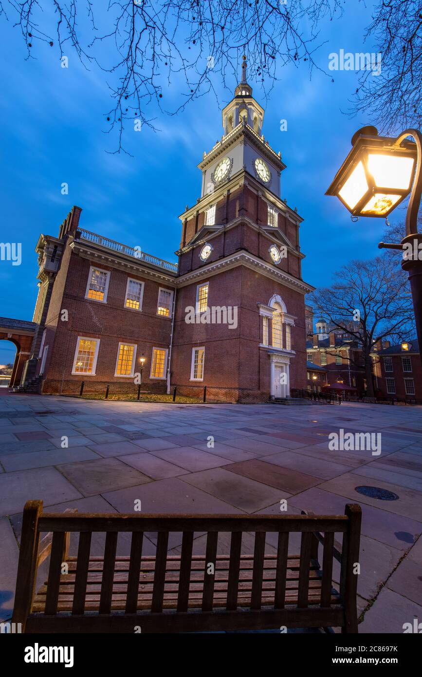 Philadelphie, PA--4 février 2020; les lumières dans les fenêtres et la tour de l'horloge de l'Independence Hall illuminent le terrain avec banc en bois et lampe de rue dedans Banque D'Images