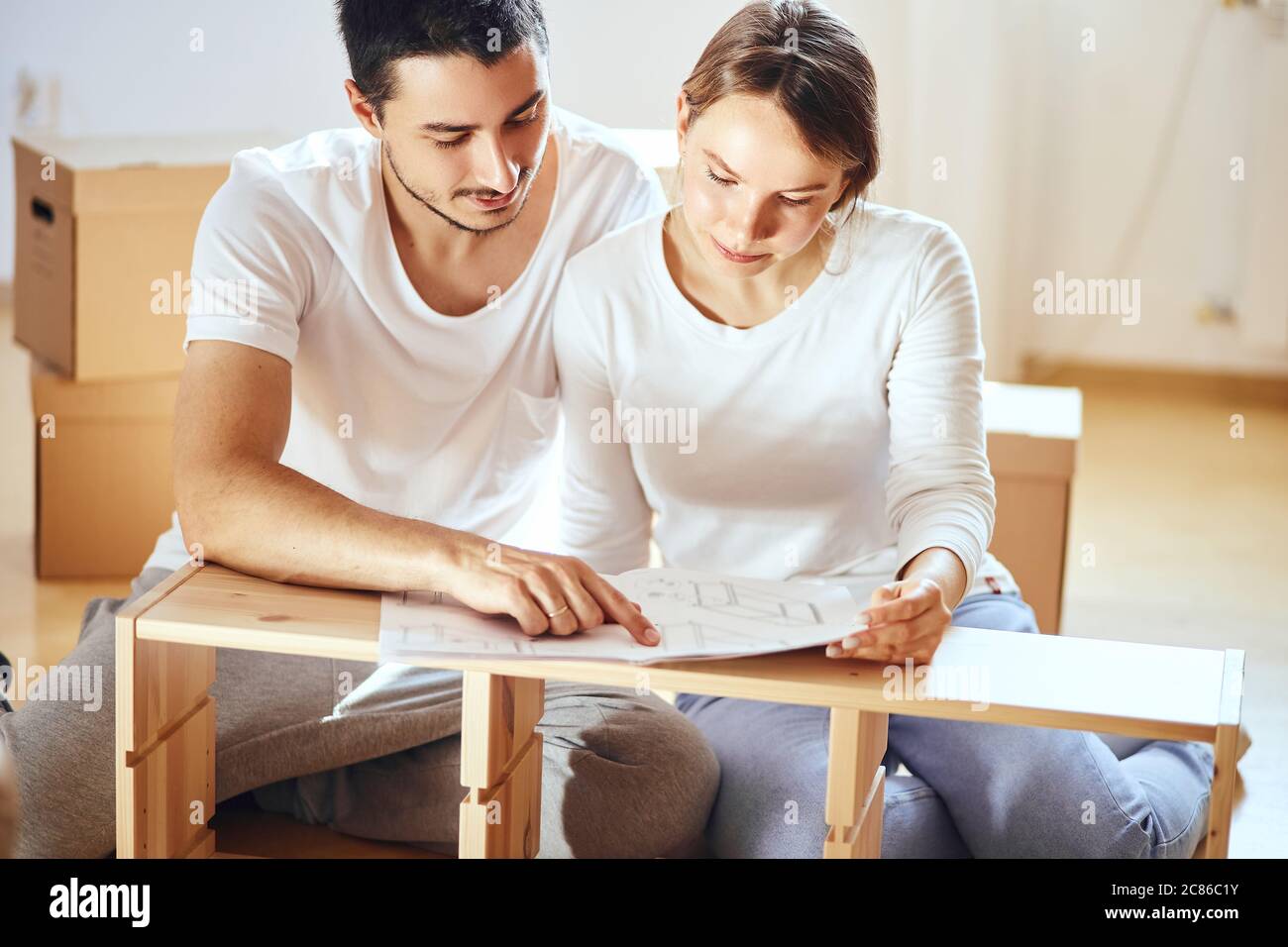 Jeune couple installant des meubles dans une nouvelle maison avec instruction Banque D'Images