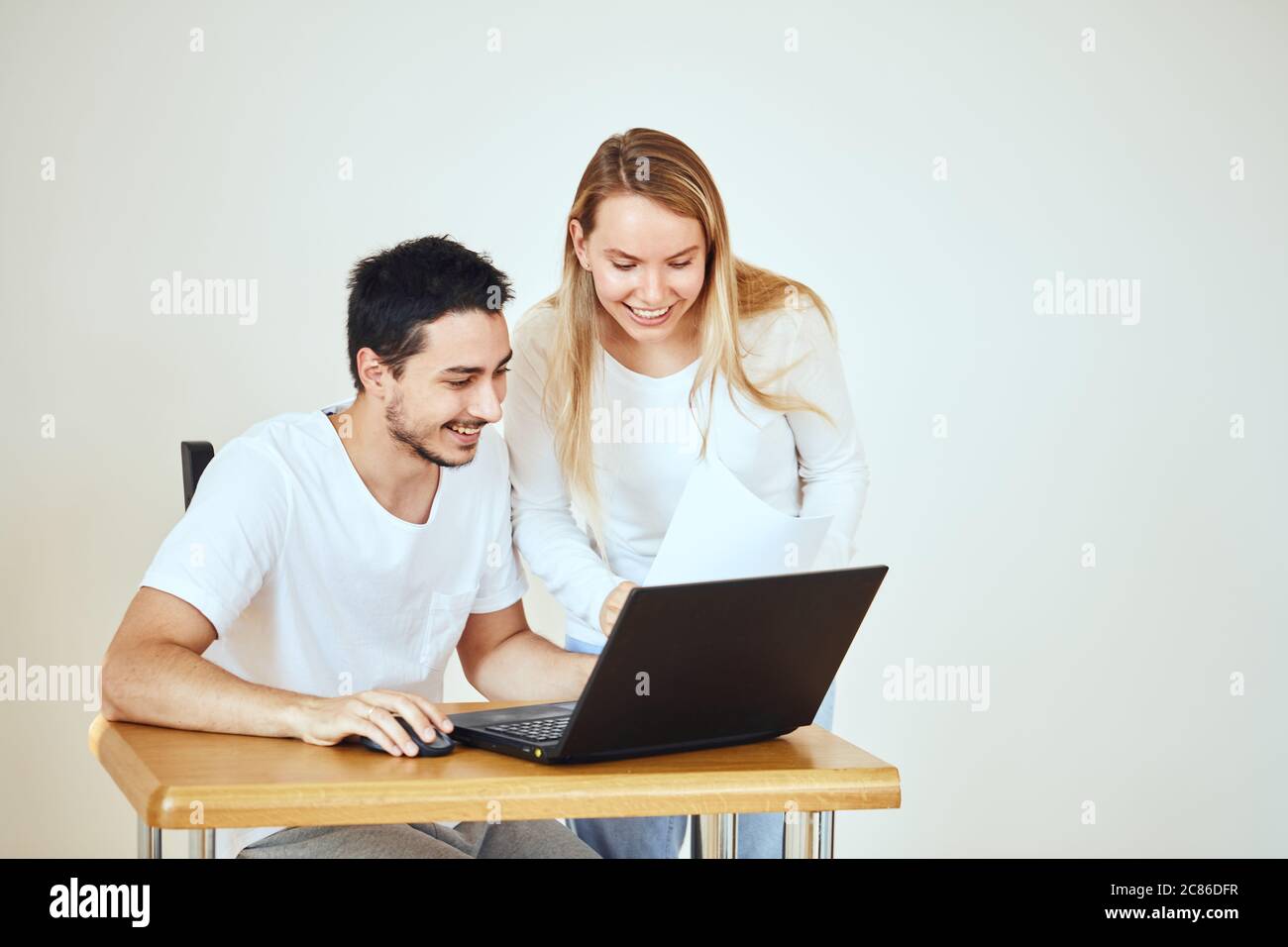 Un couple heureux vérifiant le compte bancaire sur un ordinateur portable, assis sur le bureau à la maison Banque D'Images