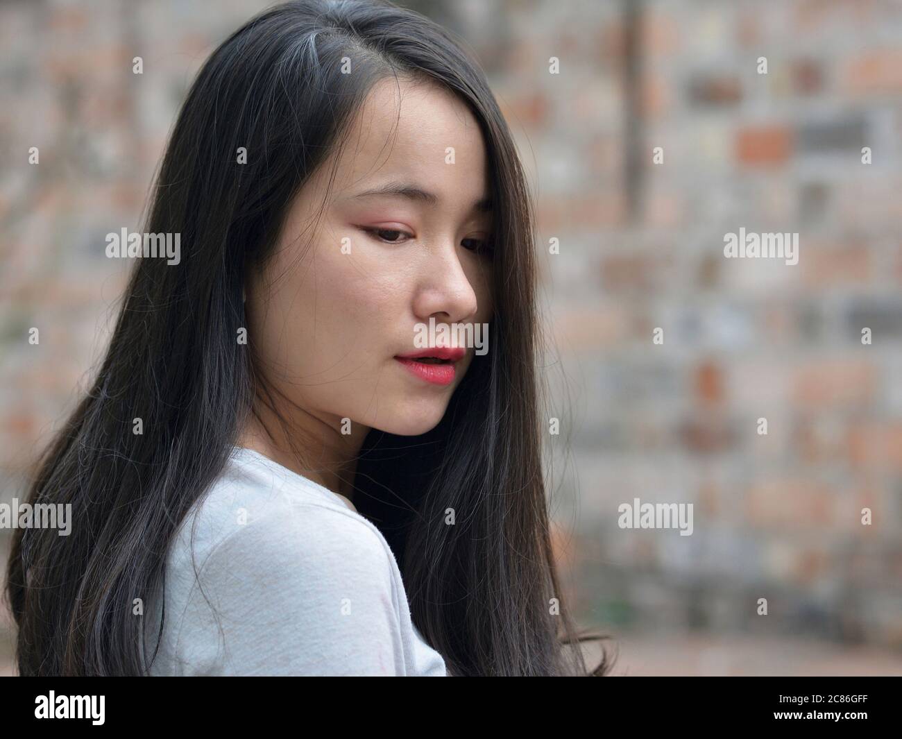 Jolie fille vietnamienne arque sa tête et abaisse ses yeux. Banque D'Images