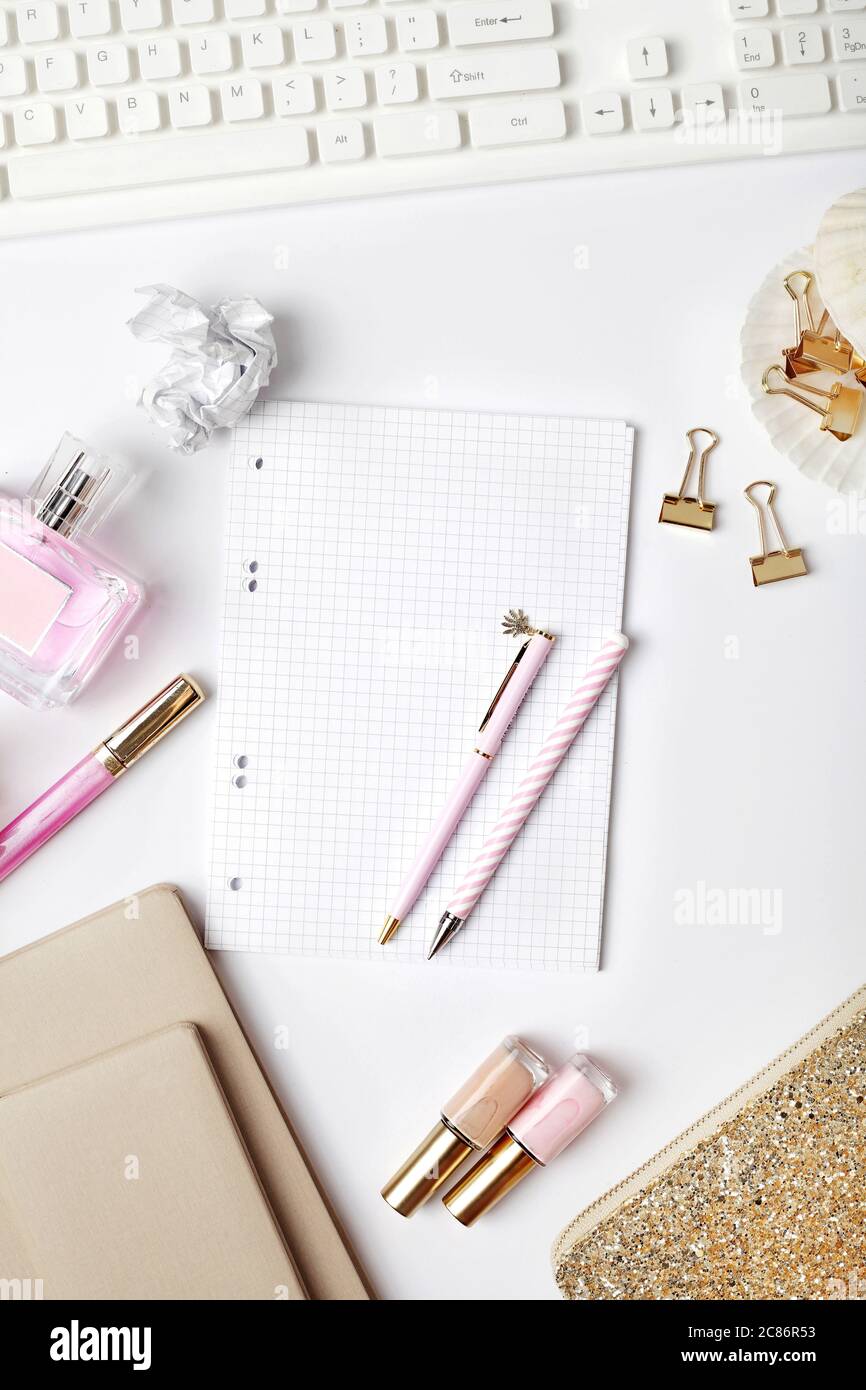 espace de travail avec clavier pour ordinateur portable, carnet d'esquisses, agenda, accessoires féminins sur fond blanc. Bureau avec table et vue sur le dessus. Banque D'Images