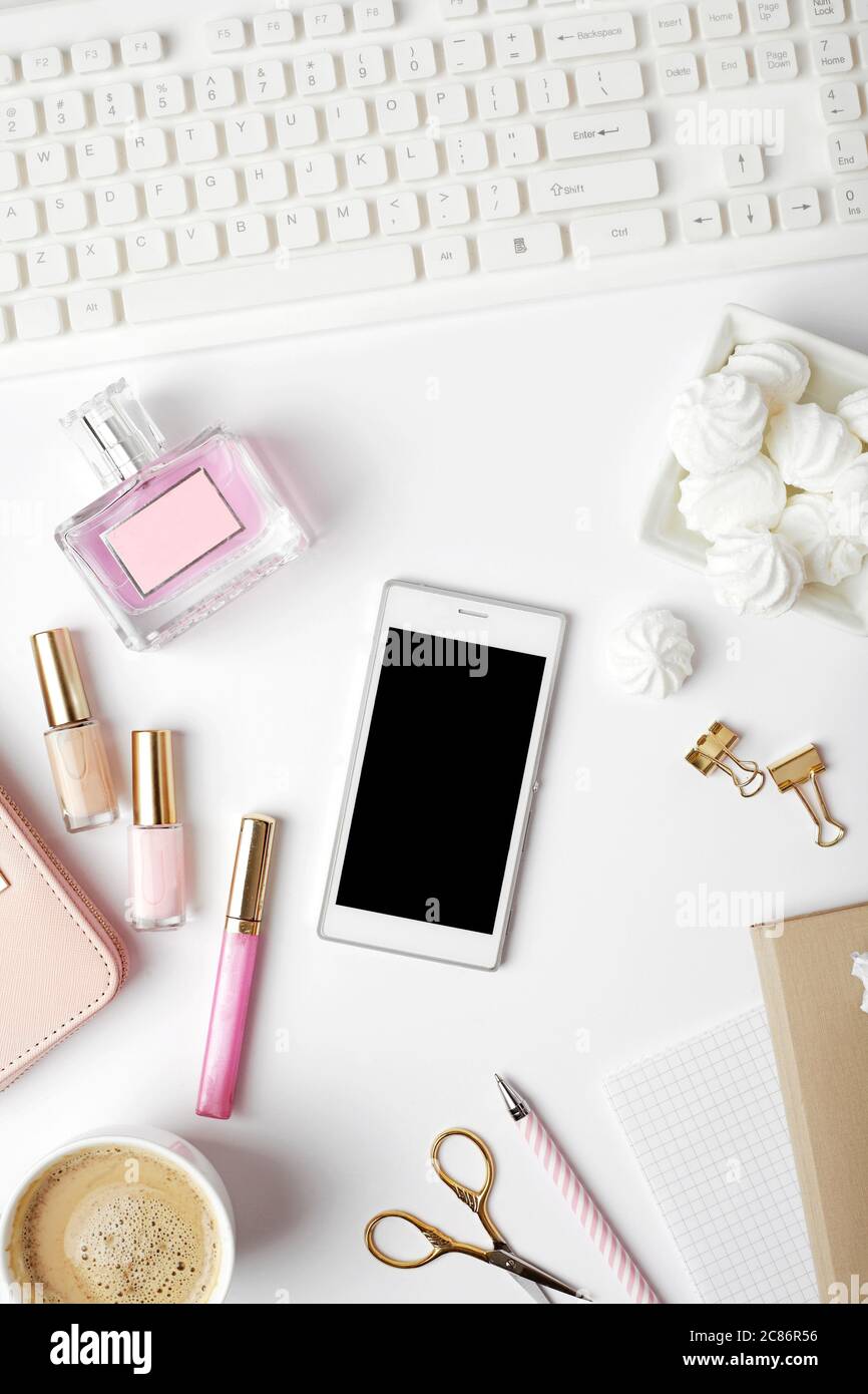 espace de travail avec clavier pour ordinateur portable, téléphone, café et accessoires pour femmes sur fond blanc. Bureau avec table et vue sur le dessus. Banque D'Images