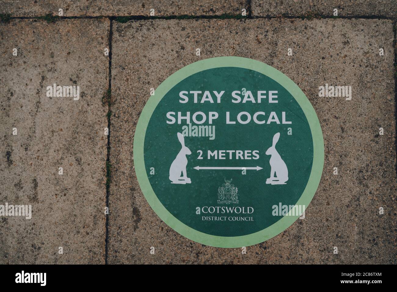 Stow-on-the-Wold, Royaume-Uni - 6 juillet 2020 : Stay Safe Shop local et 2 mètres social signe vert distançant sur un trottoir d'une rue à Stow-on-the-Wold, à un m Banque D'Images