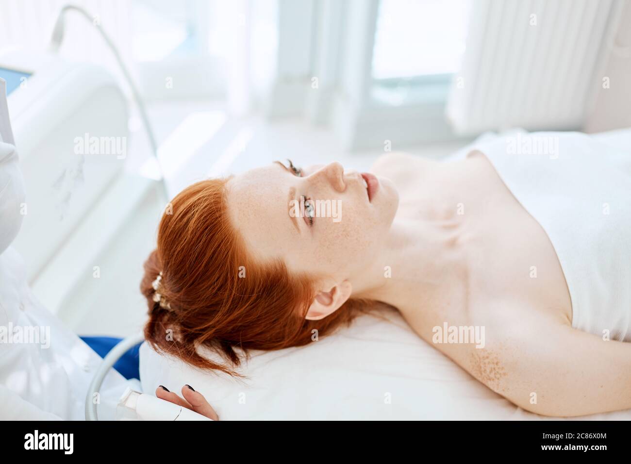 Belle femme aux cheveux rouges, couchée sur un canapé dans un centre  médical, attendant un massage de beauté. Soin du visage. Cosmétologie,  beauté et soins de la peau et traa Photo Stock -