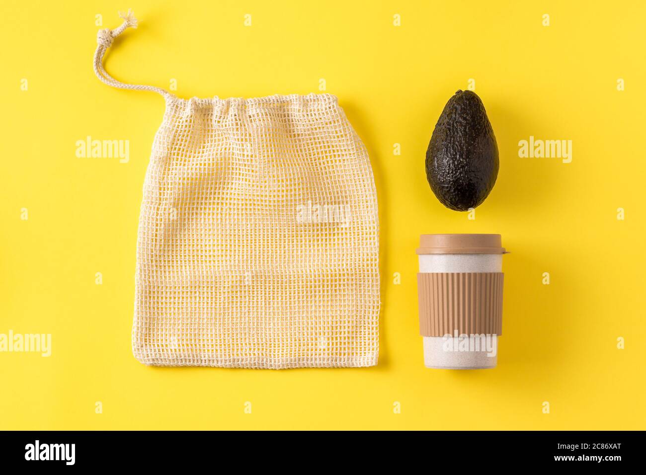Gobelet écologique portable, sac de fruits et légumes, avocat sur surface jaune. Tasse à café, sac pour l'épicerie, légumes. Flat lay, vue de dessus, mise en page créative. Banque D'Images
