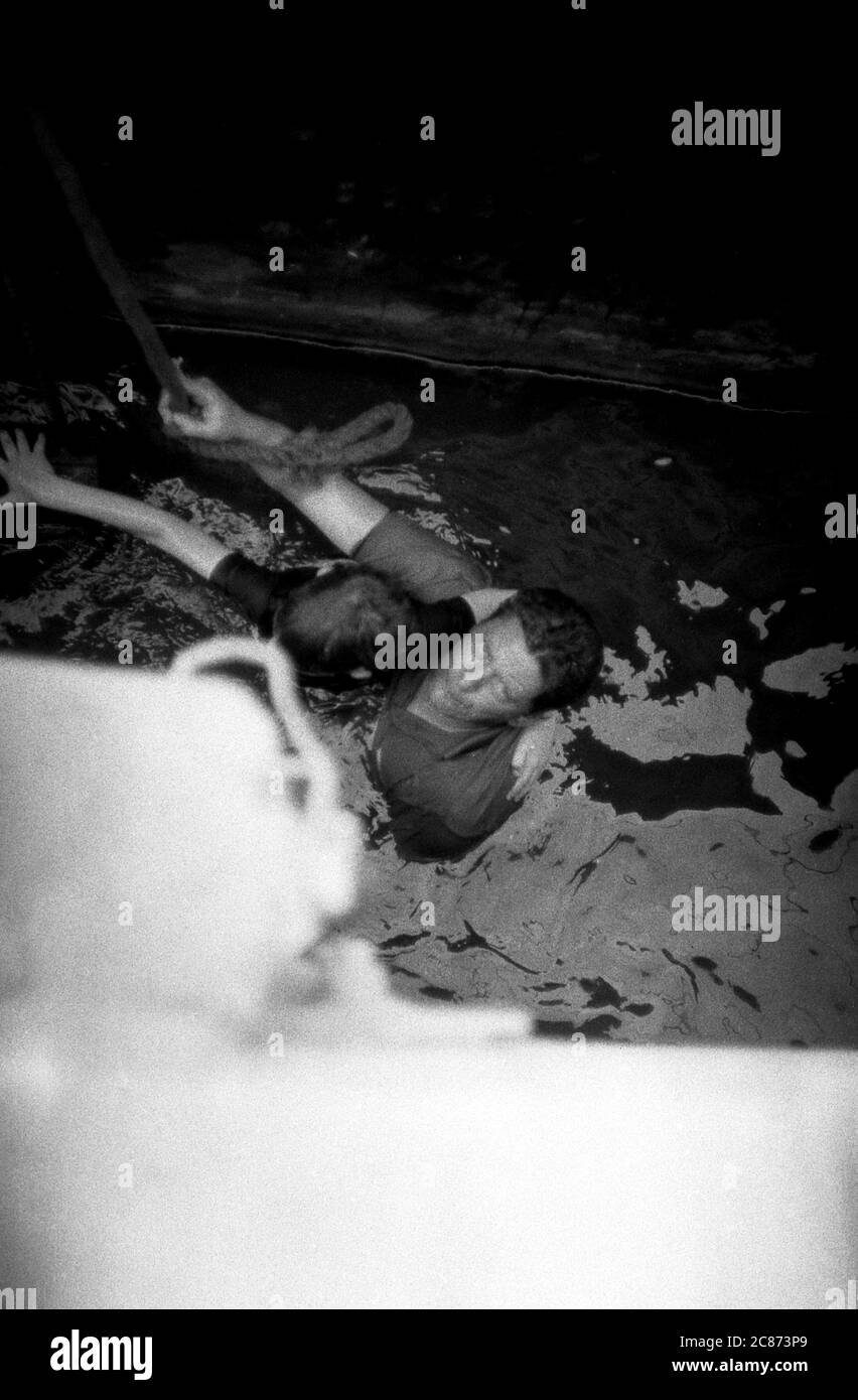 AJAXNETPHOTO. 8 JUIN 1969. PORTSMOUTH, ANGLETERRE. - LE HÉROS SAUVE L'ENFANT - ROGER BAYLISS (8YRS) A GLISSÉ ET EST TOMBÉ DU MUR NORD DU QUAI DE CARROSSAGE DANS LES EAUX MURKEY À 15 PIEDS EN DESSOUS. COINCÉ ENTRE LE MUR DU QUAI ET UNE BARGE BRITANNIQUE DES SERVICES ROUTIERS ET EN DANGER D'ÊTRE ÉCRASÉ, IL A ÉTÉ SECOURU PAR MR WARD, UN PASSAGER DANS UN VÉHICULE DE VOYAGE QUI A FAIT DES PASSES INESSÉES DANS LE QUAI, NAGÉ SOUS LA BARGE ET EST VENU EN AIDE À ROGER, UN NON NAGEUR, TANDIS QUE LES ASSISTANTS DOCKSIDE ONT TRANSPORTÉ LA PAIRE EN SÉCURITÉ. PHOTO:JONATHAN EASTLAND/AJAX REF:356923 202206 55 Banque D'Images