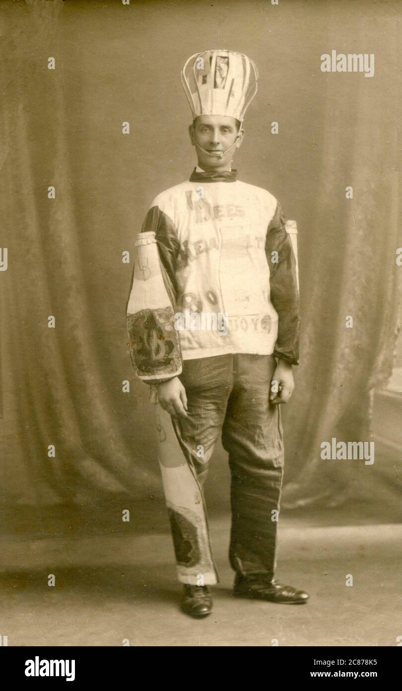 Homme dans un costume de robe plutôt inhabituel, probablement comme United Dairies comme U Dees semble être l'argot pour la compagnie, mais les bouteilles sur ses manches donnent le jeu loin. Date: c.1910 Banque D'Images