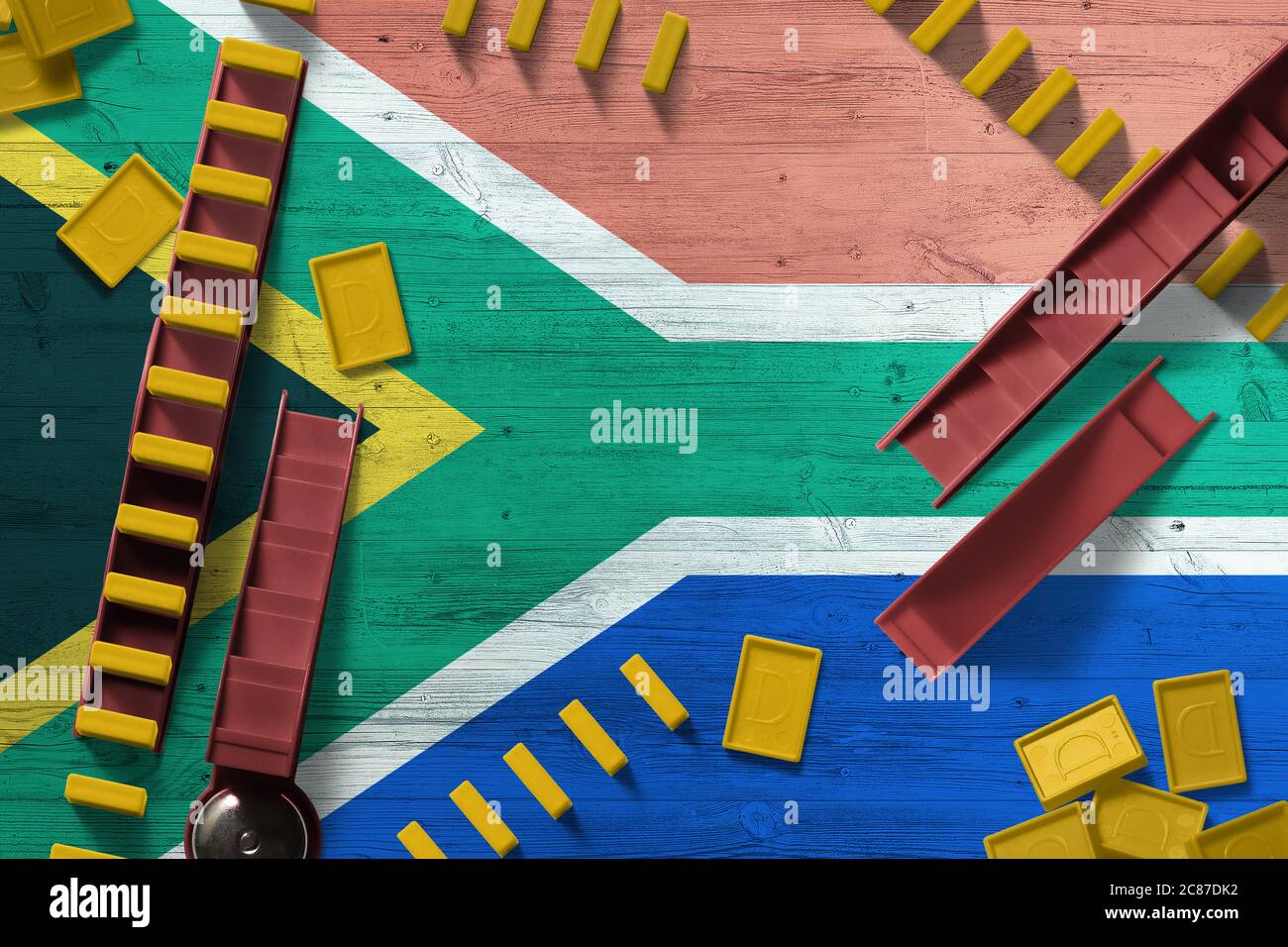 Drapeau sud-africain sur fond national avec dominos sur table en bois. Vue de dessus. Concept de jeu. Banque D'Images