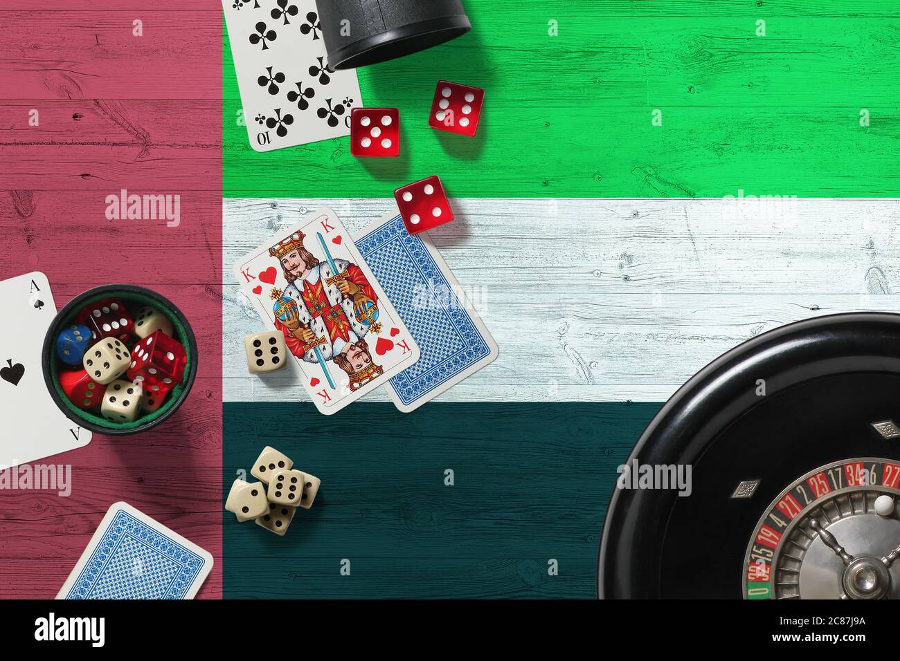 Thème du casino des Émirats arabes Unis. Jeu de poker Aces, cartes et jetons sur table rouge avec drapeau national en bois. Jeux et Paris. Banque D'Images