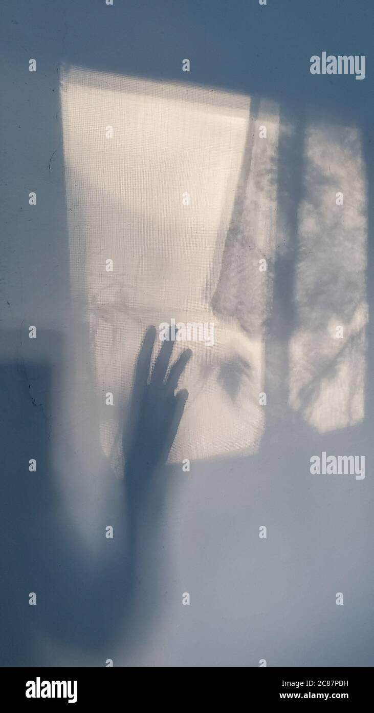 Silhouette d'ombre de main féminine essayant d'atteindre la fenêtre. Concept de dépression. Banque D'Images