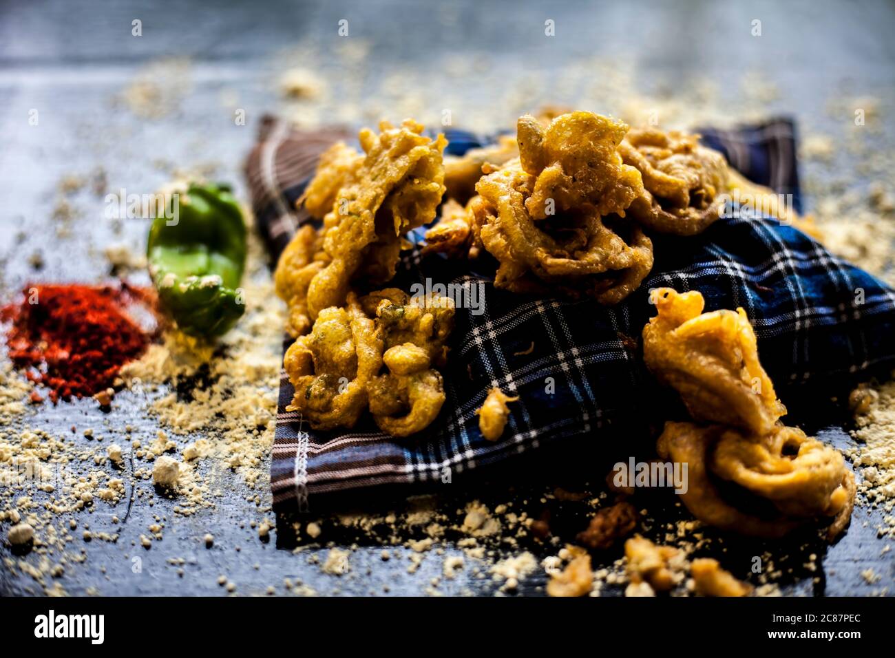 Célèbre kanda bhaji ou kanda bhajiya ou kanda pakora dans un récipient sur une surface noire avec la farine de pois chiches, les épices, et tous les autres ingrédients pour Banque D'Images