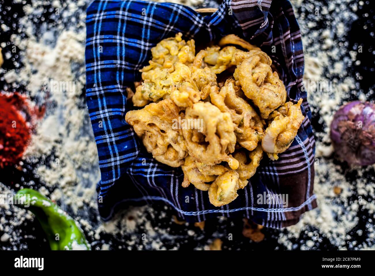 Célèbre Kanda bhaji ou Kanda bhajiya ou Kanda pakora dans un récipient sur une surface noire avec de la farine de pois chiches, des épices, des oignons, et tous les autres ingrédients Banque D'Images