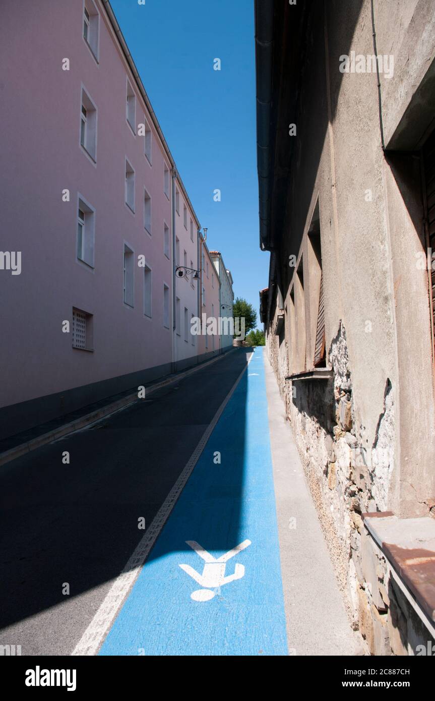 Rue étroite avec sentier piéton bleu dans la ville d'Izola, Slovénie. Vue en profondeur. Banque D'Images