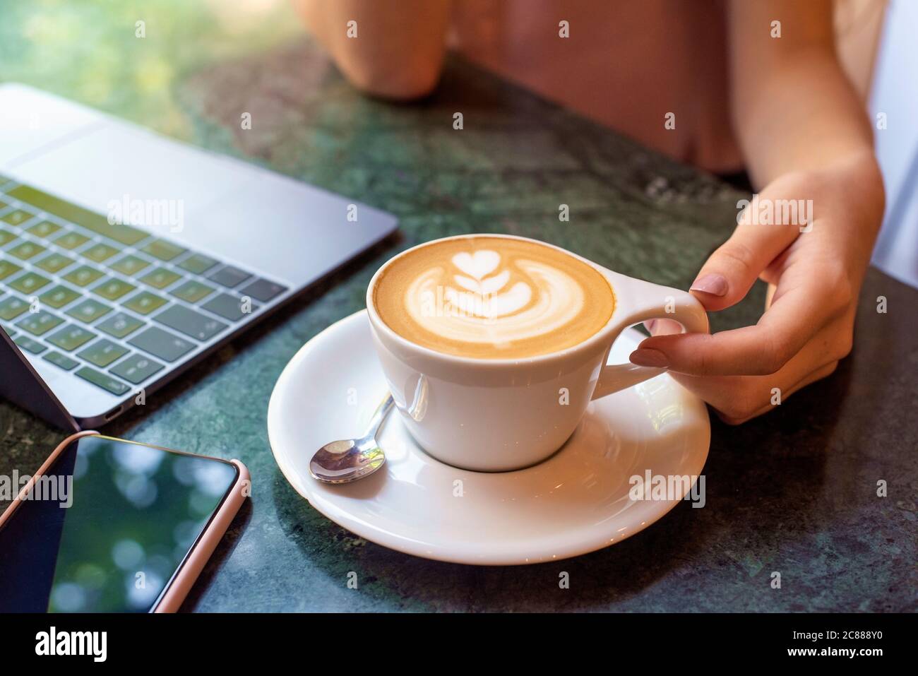 Photo en grand angle d'une femme méconnaissable assise au comptoir du café et buvant son cappuccino. Banque D'Images