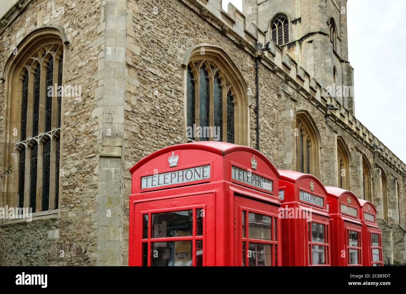 Les téléphones britanniques de style ancien vus alignés par une grande église dans la ville universitaire de Cambridge. Banque D'Images
