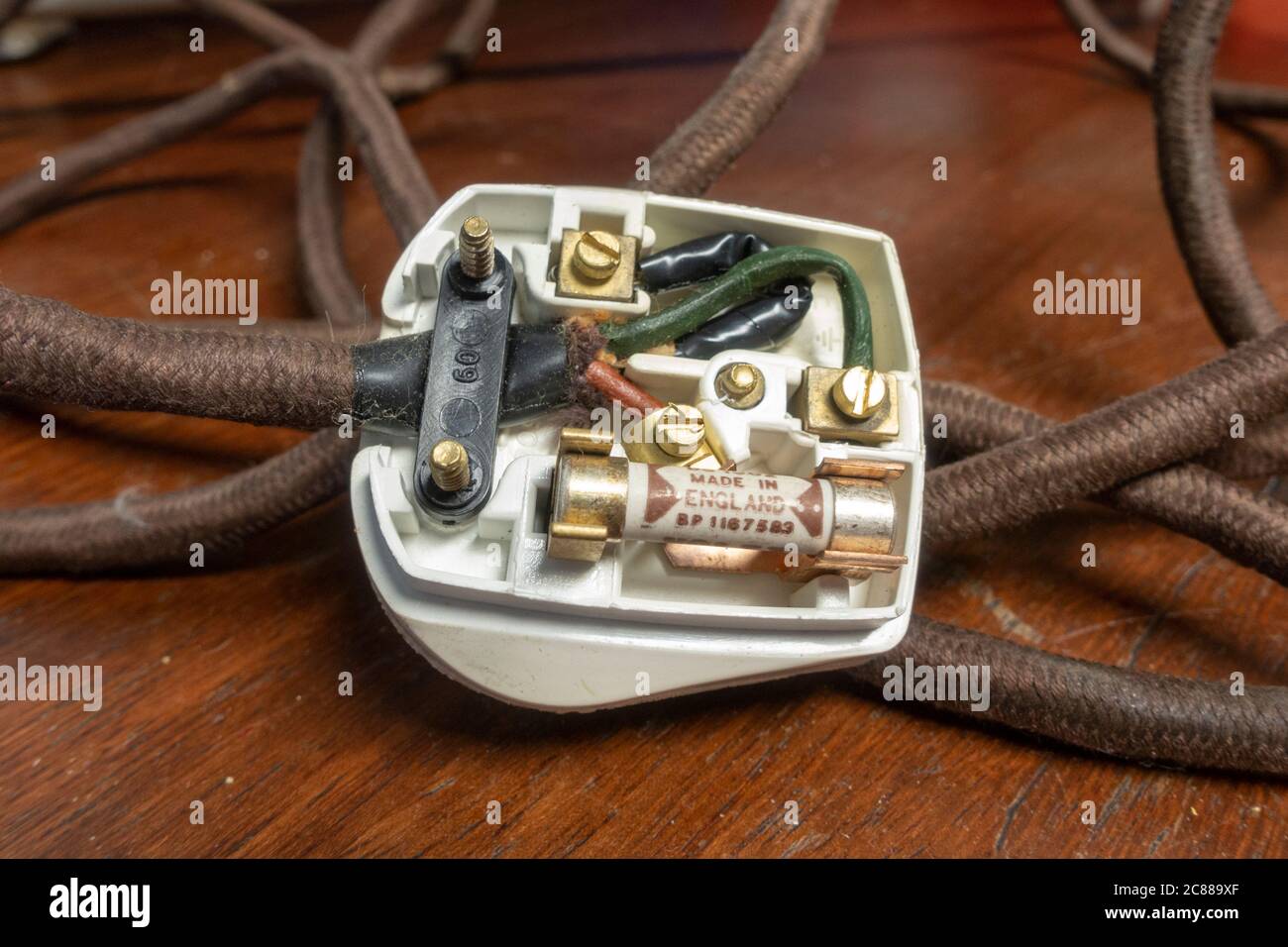 Une ancienne fiche britannique avec des fils noirs (neutre), verts (terre) et bruns (sous tension). Banque D'Images