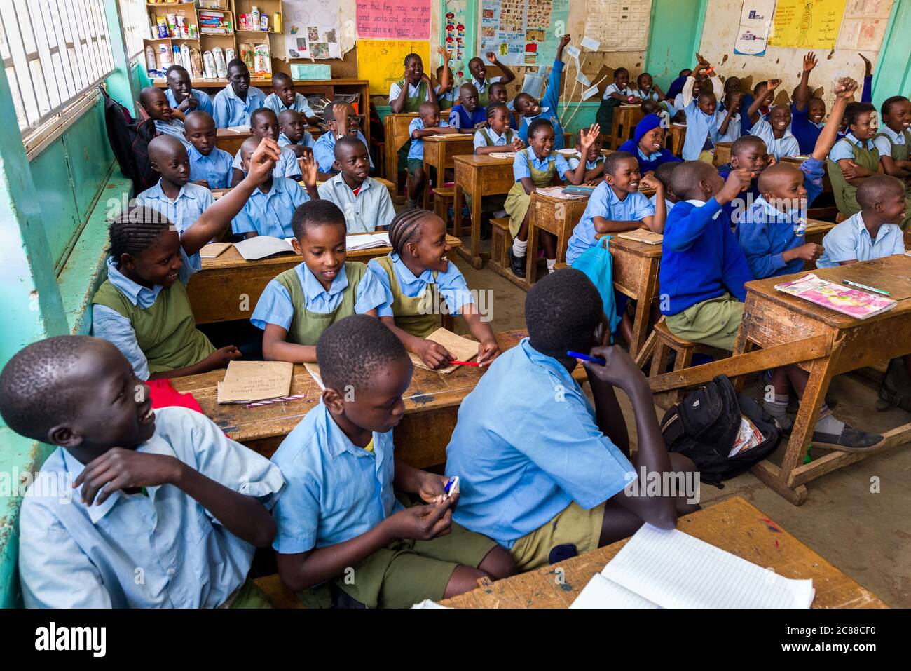 Les enfants de l'école secondaire en uniforme étaient assis à des bureaux en bois à l'écoute de leur enseignant pendant la classe, Nairobi, Kenya Banque D'Images