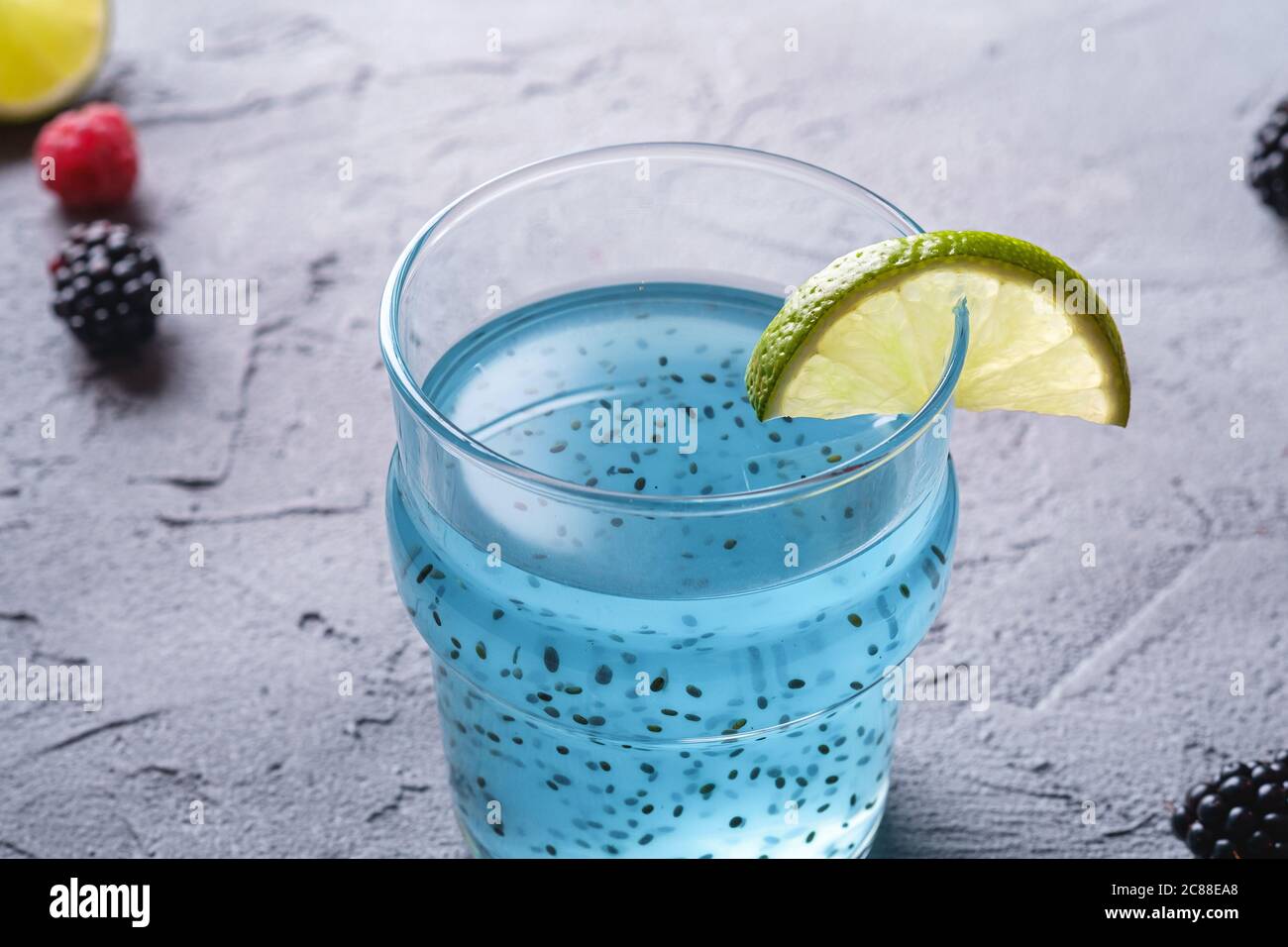 Délicieux cocktail de couleur bleue avec graines de basilic chia, tranche de citron vert, framboise et mûres de mûre en verre, boisson d'été saine Banque D'Images