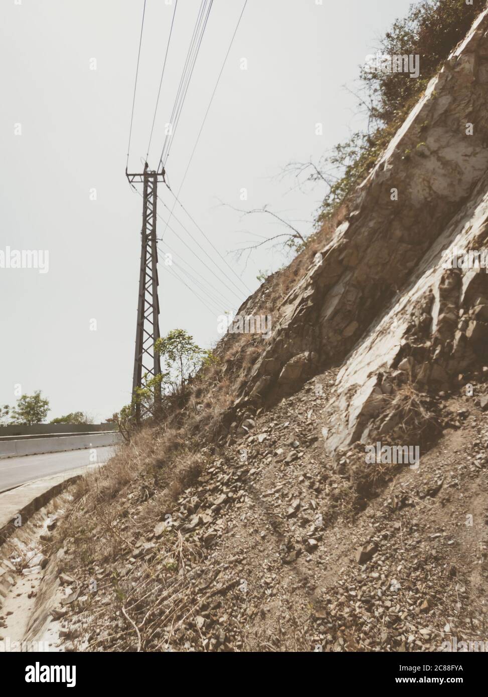 Asphalte sec route d'automobile vide avec pôle électrique près des rochers lors d'une journée ensoleillée d'été. Présentation du concept de voyage en voiture. Format vertical des articles Banque D'Images