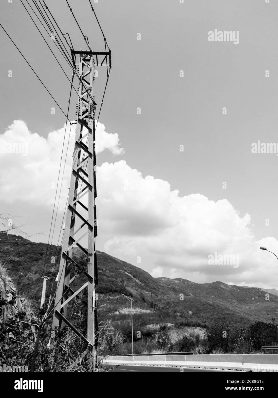Asphalte sec route d'automobile vide avec pôle électrique près des rochers lors d'une journée ensoleillée d'été. Présentation du concept de voyage en voiture. Format vertical des articles Banque D'Images
